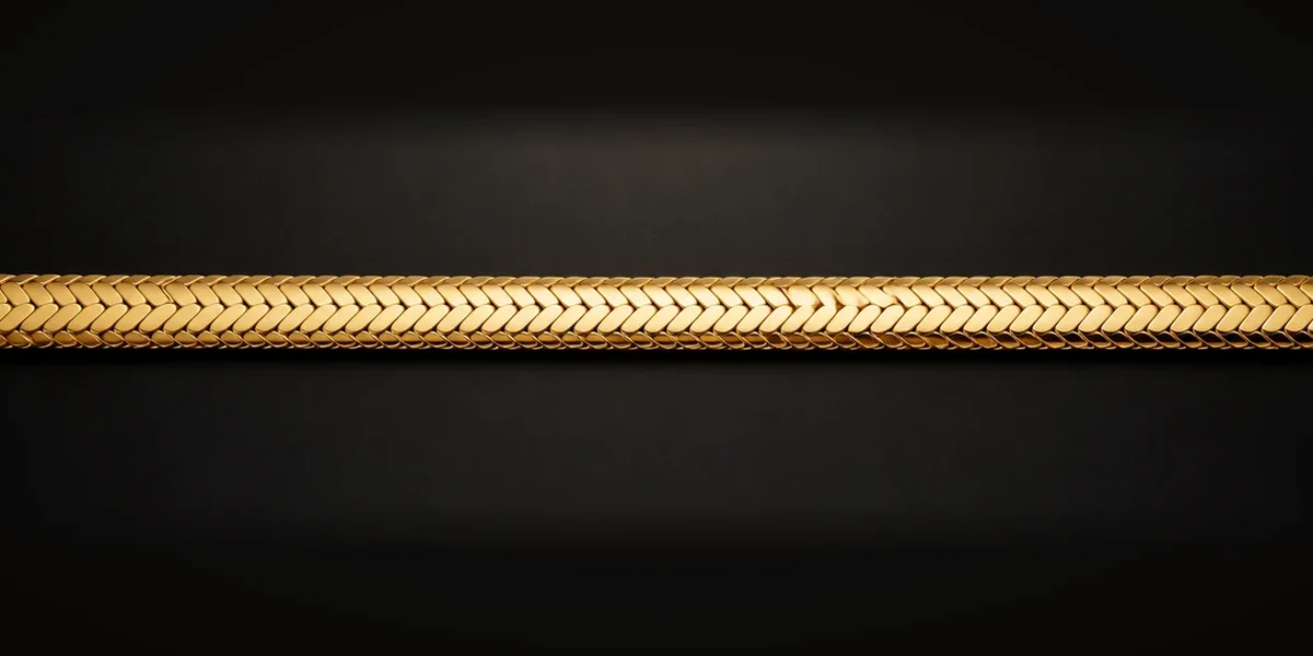 Goldene Fischgrätkette – Flache, schräg angeordnete Segmente greifen dicht ineinander und bilden ein gleichmäßiges Fischgrätmuster.